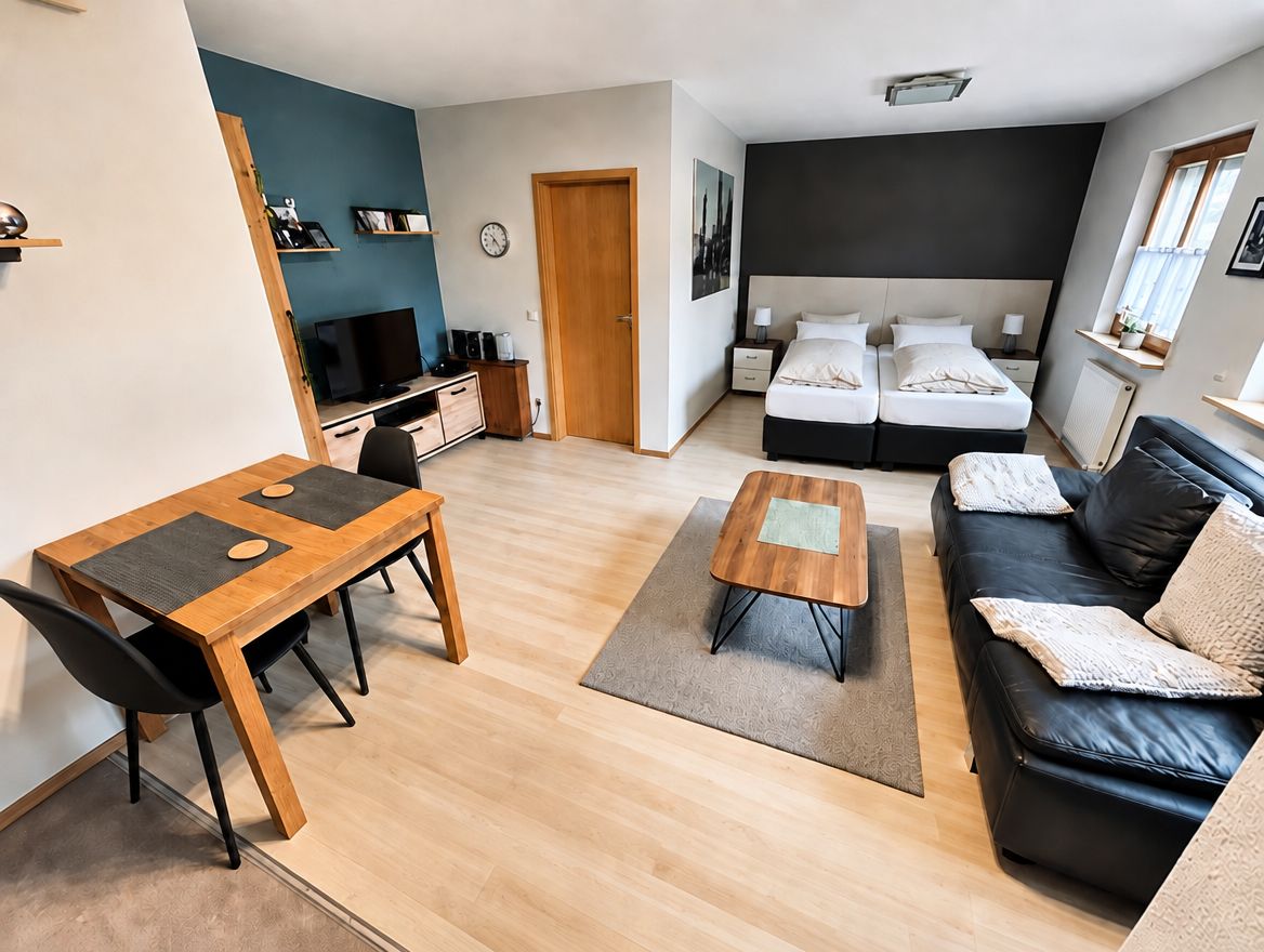Ferienwohnung in Würzburg: Wohnraum mit Esstisch, Sofa, Fernseher und Doppelbett
